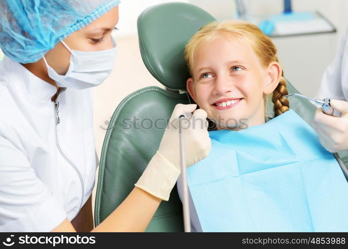 Tooth check. Cute smiling girl in at dentist sitting in armchair