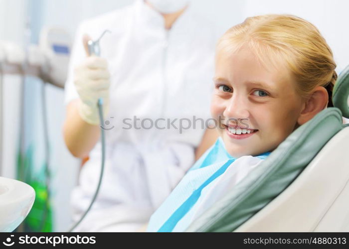 Tooth check. Cute smiling girl in at dentist sitting in armchair