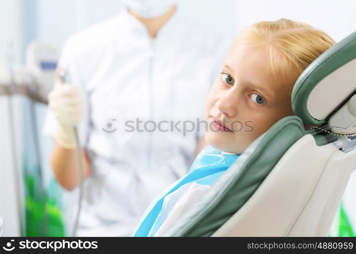 Tooth check. Cute smiling girl in at dentist sitting in armchair