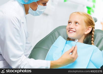 Tooth check. Cute smiling girl in at dentist sitting in armchair