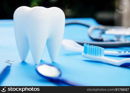 Tooth model and dentist tools on blue background. Dentistry concept.