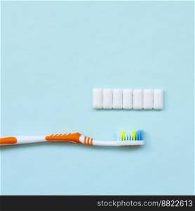 Toothbrush and chewing gums lie on a pastel blue background. Top view, flat lay. Minimal concept.. Toothbrush and chewing gums lie on a pastel blue background. Top view, flat lay. Minimal concept