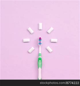 Toothbrush and chewing gums lie on a pastel pink background. Top view, flat lay. Minimal concept.. Toothbrush and chewing gums lie on a pastel pink background