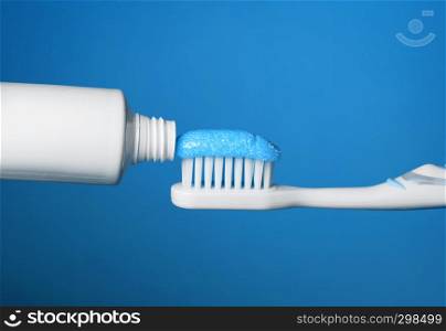 Toothbrush with toothpaste close up on blue background.