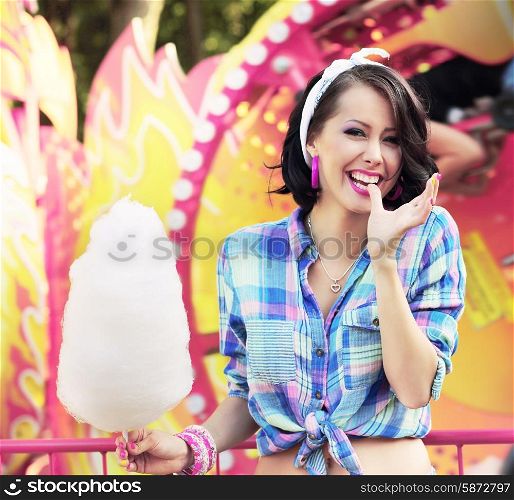 Toothy Smile. Young Woman with Cotton Candy in Amusement Park
