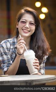 toothy smiling face happiness emotion of younger asian woman with cool drink bottle in hand