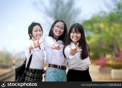 toothy smiling face of asian teenager group sign i love you by hand