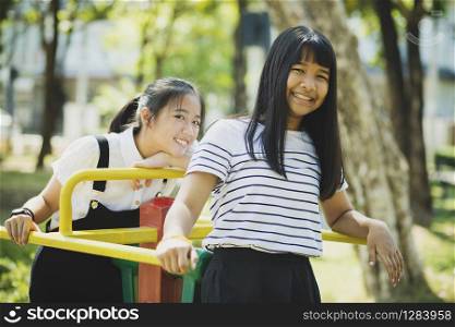 toothy smiling face of asian teenager relaxing in children playground