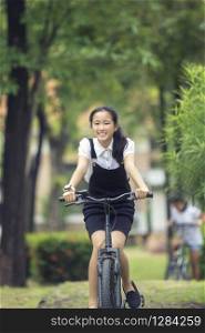 toothy smiling face of asian teenager riding bicycle in green park
