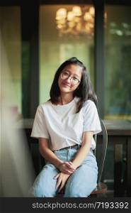 toothy smiling face of asian teenager sitting on wood desk