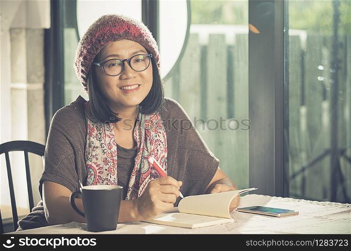 toothy smiling face of asian woman reading pocket book in coffee shop