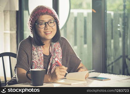 toothy smiling face of asian woman reading pocket book in coffee shop
