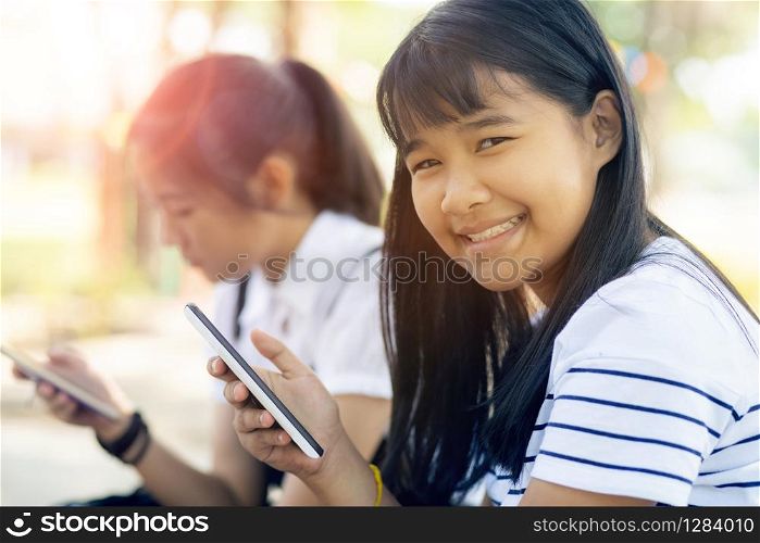 toothy smiling face of cheerful asian teenager holding smart phone in hand