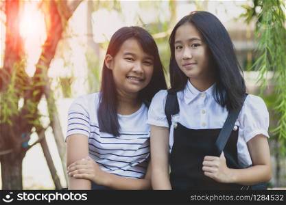 toothy smiling face of two asian teenager standing outdoor