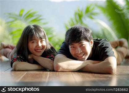 toothy smiling happiness face of asian younger couples lying on wood floor
