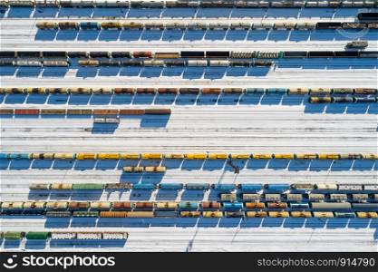 Top aerial view of many colorful freight trains on the parallel railroad tracks at winter, industrial concept