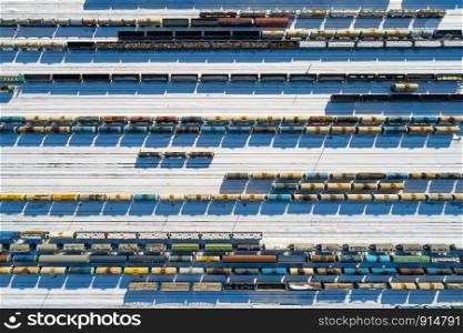 Top aerial view of many colorful freight trains on the parallel railroad tracks at winter, industrial concept