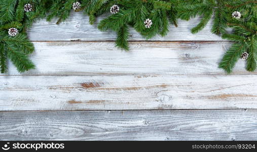 Top border of Christmas tree fir branches and pine cones on rustic wood in flat lay format