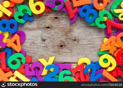 Top border of colorful toy magnetic letters and numbers over a wooden background