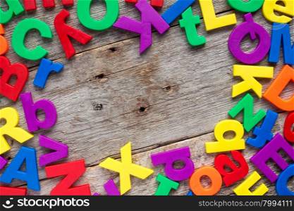 Top border of colorful toy magnetic letters over a wooden background