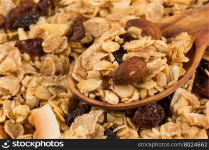 Top close view of a dry mix of fruit and almon nuts cereal and spoon