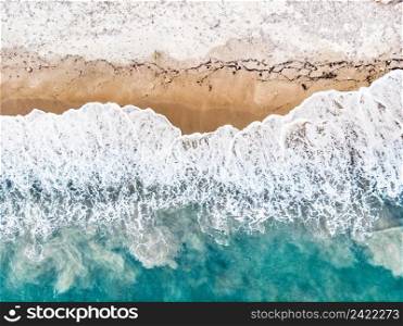 Top down view. Sea waves and sand beach shore. Summertime.. Aerial view. Sea waves and sandy beach