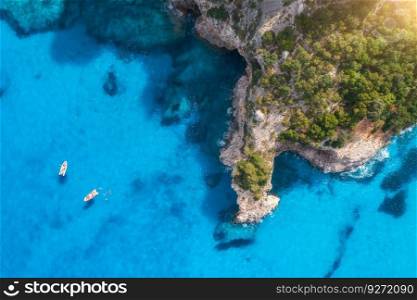 Top drone view of boats and yacths in transparent azure water at sunset. Aerial view of boats in clear blue sea, rocks, green forest. Travel in Sardinia, Italy. Tropical seascape. Nature. Sea bay