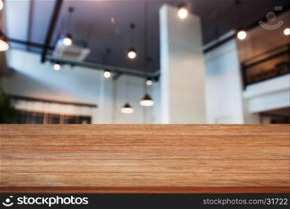 Top of wooden table with abstract blur coffee shop interior for background