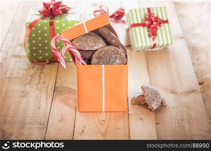 Top open gift box full of gingerbread and colorful candies on a wooden table