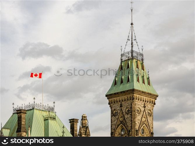 Top part of East Block of Parliament Hill with Canadian flag waving in Ottawa, Canada
