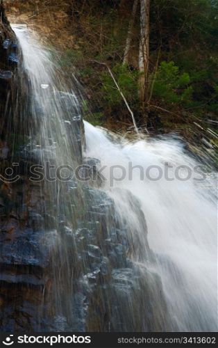 Top part of high mountain waterfall in dark wild Carpathian forest (Manjava, Ivano-Frankivsk Region, Ukraine).