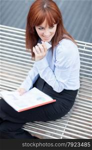 Top shot of businesswoman with charts sitting outside on a metal bank