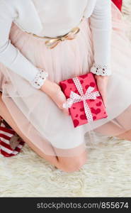 Top shot of girl wearing dress holding Christmas gift and sitting on a carpet