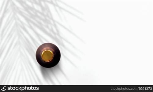 Top up view dark brown beer bottle under palm tree isolated on white.