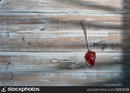Top up view Strawberry jam in white spoon. over wooden table.