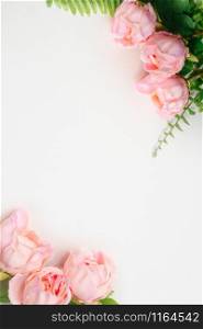 Top vertical view of pink Peonies artificial flowers and green fern leaves on white blank background