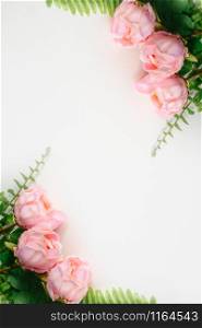 Top vertical view of pink Peonies artificial flowers and green fern leaves on white blank background