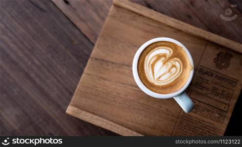 Top view a cup of coffee on wooden table background with beautiful latte art at coffee shop.Latte coffee is a drink with a pleasant aroma. And has a delicious flavor, refreshing in the workday and relaxing on holidays