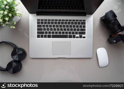 Top view a laptop with camera on white table with mouse and headphone.Home interior or office background