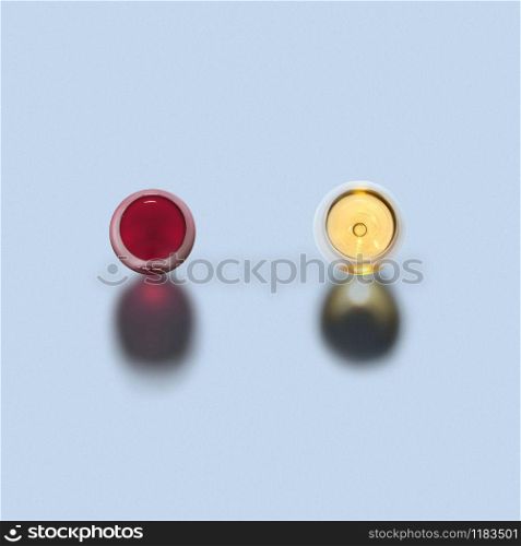 Top view above two glasses of red and white wine on a light grey background with dark shadows, copy space.. Two glasses of red and white wine. Top view.