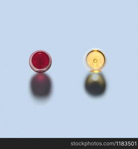 Top view above two glasses of red and white wine on a light grey background with dark shadows, copy space.. Two glasses of red and white wine. Top view.