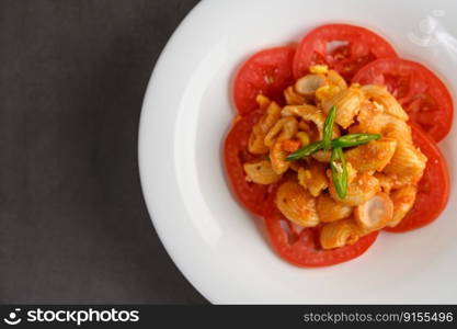 Top view and close up of pipe rigate italian pasta with tomato sauce and egg, chili and fresh tomato slice in white plate, copy space and selective focus