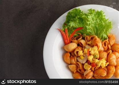 Top view and close up of pipe rigate italian pasta with tomato sauce and egg, chili and fresh tomato slice in white plate, copy space 
