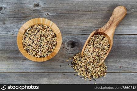 Top view angled shot of a wooden bowl and scoop filled with whole grain rice on rustic wood.