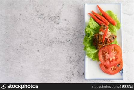 Top view appetizers with spicy sardine mixed with herb placed on lettuce in ceramic tray with slice tomato and red chili, copy space

