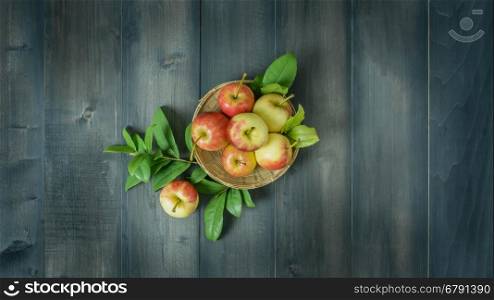 Top view apple on wooden background. Top view red and yellow apple with leaves and bamboo basket on wooden background with free space for text