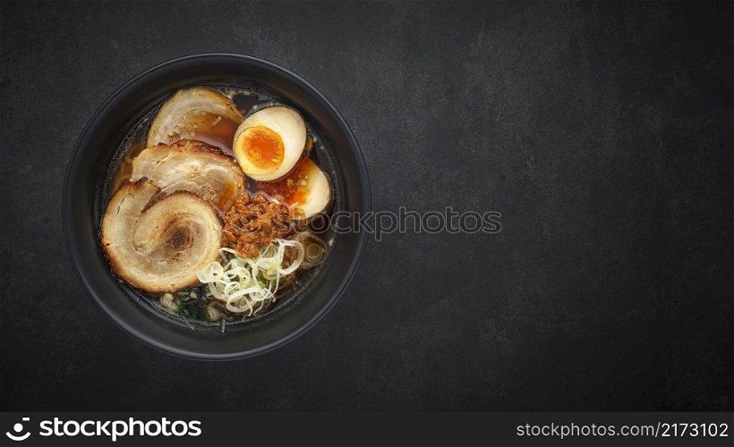 top view Asian ramen noodle soup with Chashu  Japanese braised pork belly , Nitamago egg, sliced spring onion, Ajitsuke Menma and dried seaweed on dark texture background with copy space for text
