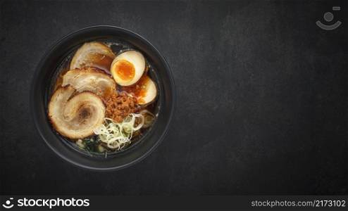 top view Asian ramen noodle soup with Chashu  Japanese braised pork belly , Nitamago egg, sliced spring onion, Ajitsuke Menma and dried seaweed on dark texture background with copy space for text