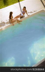 Top view at two young women having fun by the swimming pool at hot summer day