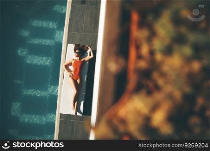Top view at young slim beautiful woman in swimsuit sunbathing near swimming pool